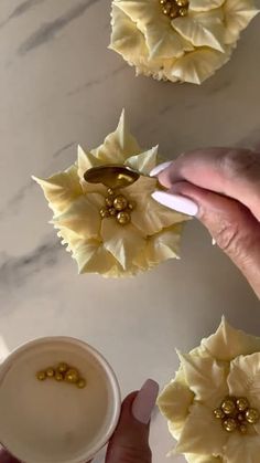 someone is holding some flowers in front of a cup and saucer on a table