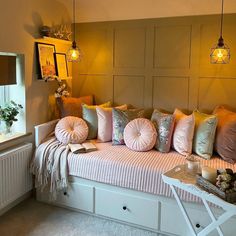 a white day bed with lots of pillows on top of it and some lights hanging from the ceiling