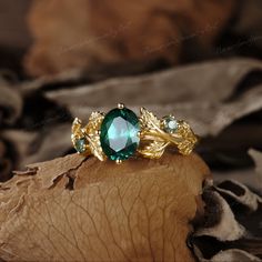 a green ring sitting on top of a piece of wood next to a leafy plant