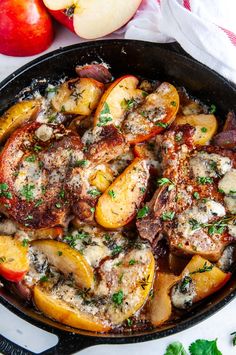 a skillet filled with meat, potatoes and apples on top of a white table