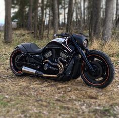 a black motorcycle parked in the woods next to some trees