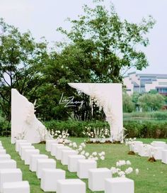 an outdoor ceremony setup with white chairs and flowers on the grass in front of it