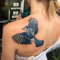 a woman with a blue bird tattoo on her back