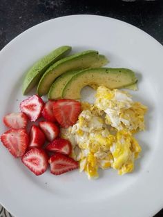 a white plate topped with eggs, strawberries and avocado