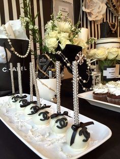 the desserts are decorated with black and white ribbons, pearls, and flowers in vases