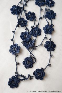 a blue crocheted necklace with flowers on it