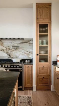 a kitchen with marble counter tops and wooden cabinets, along with a black stove top oven