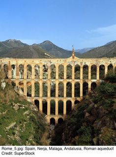 an old stone bridge in the middle of mountains