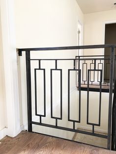 an iron railing in the corner of a room with wood floors and white walls behind it