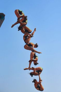 a group of women in bikinis doing tricks on a surfboard