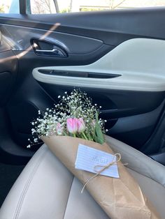 a bouquet of tulips and baby's breath wrapped in brown paper sitting on the back seat of a car