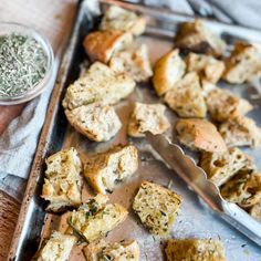 there are many small pieces of bread on the tray next to some spoons and seasoning