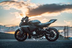 the motorcycle is parked on the side of the road in front of a sunset sky