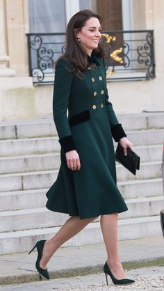 a woman in green coat and heels walking down steps