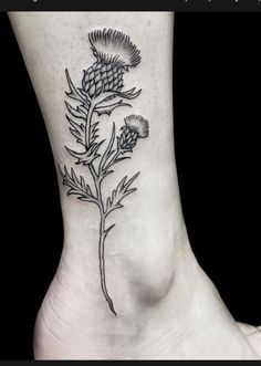 a black and white photo of a flower on the side of a woman's foot