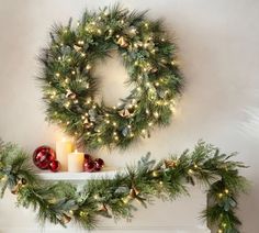 a christmas wreath and candles on a mantle