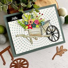 a handmade card with a wheelbarrow and flowers on it, surrounded by other crafting supplies