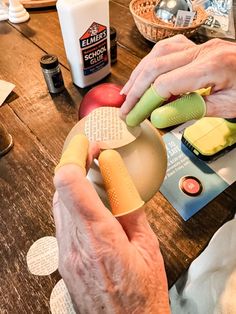 an older person is doing crafts on a wooden table with other items around him and his hands are holding the object