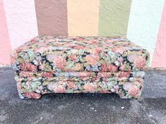 an upholstered bench sitting in front of a multicolored wall