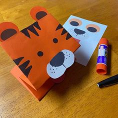 an orange paper bag with a cut out tiger on it next to markers and pens