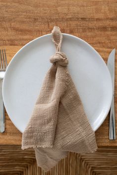 a white plate topped with a napkin next to a fork and knife on top of a wooden table