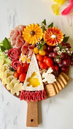 a platter with fruits and vegetables arranged in the shape of a triangle on a wooden paddle