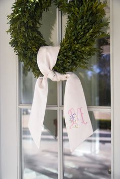 a wreath on the front door with a monogrammed bow