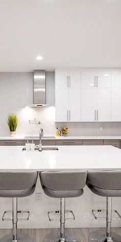 a kitchen with white counter tops and gray stools