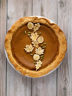 a pie with leaves on it sitting on top of a wooden table