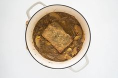 a pot filled with stew sitting on top of a white counter next to a wooden spoon