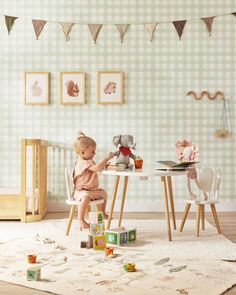 a toddler sitting at a table with toys in front of him and on the floor