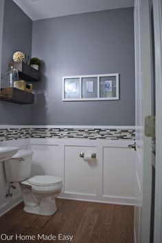 a white toilet sitting next to a sink in a bathroom under a framed picture on the wall