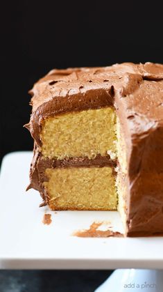 a piece of cake with chocolate frosting is on a white plate and there is a slice missing from the cake