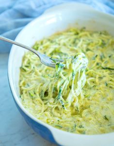 a white bowl filled with broccoli and cheese sauce on top of a blue towel