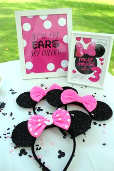 minnie mouse ears with pink and white polka dots are on a table next to a framed photo