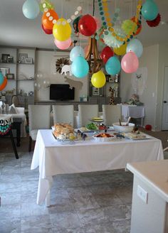 a dining room table with balloons hanging from it's ceiling and food on the table