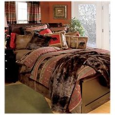 a bedroom with a bed covered in brown and red sheets, pillows and blankets on top of it