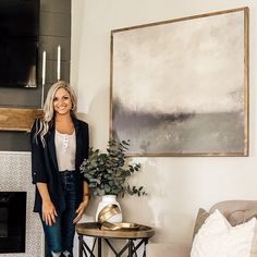 a woman standing next to a painting in a living room