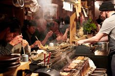 people sitting at a table with food on it and chopsticks in their hands