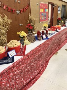 a long table covered in red and white cloth with desserts on top of it