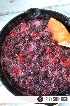 a skillet filled with berries on top of a wooden table