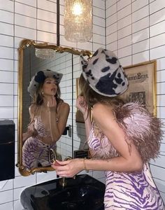 a woman standing in front of a bathroom mirror looking at her reflection wearing a zebra print dress