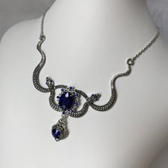 "This Medusa inspired necklace is made with a large antiqued silver plated double snake motif, filigrees and findings. Sparkling glass crystals in DARK SAPPHIRE BLUE accent the eyes and centerpiece. Snakes are 3 5/8\" across with a total height of approximately 4 inches from snake tale to bottom of pendant drop. The very center jeweled portion is 2 1/4\" tall. Necklace is adjustable 15-18\" with a lobster clasp and chain extender in the back. If you would like a different length or stone color, Luxury Ornate Green Necklace, Luxury Blue Victorian Necklaces, Green Snake Necklace, Blue Medieval Necklace, Blue Gothic Metal Necklace, Medusa Snake, Antique Silver Necklace, Dark Sapphire, Choker Pendant