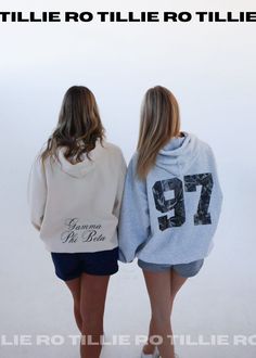 two women standing next to each other wearing sweatshirts with numbers on the front and back