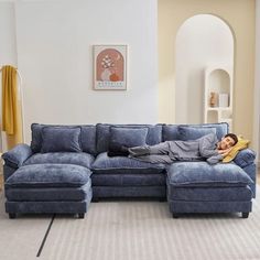 a man laying on top of a blue couch in a living room