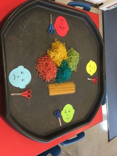 a tray with noodles, scissors and other things on it that are cut out to look like faces