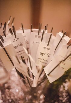 a vase filled with lots of paper tags on top of a table covered in glitter