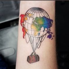 a colorful tattoo with a hot air balloon flying over the world on it's arm