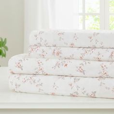 a stack of white sheets sitting on top of a table next to a potted plant