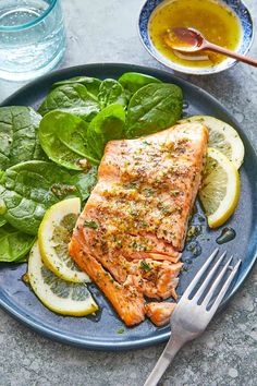 grilled salmon with lemons and spinach on a blue plate next to water